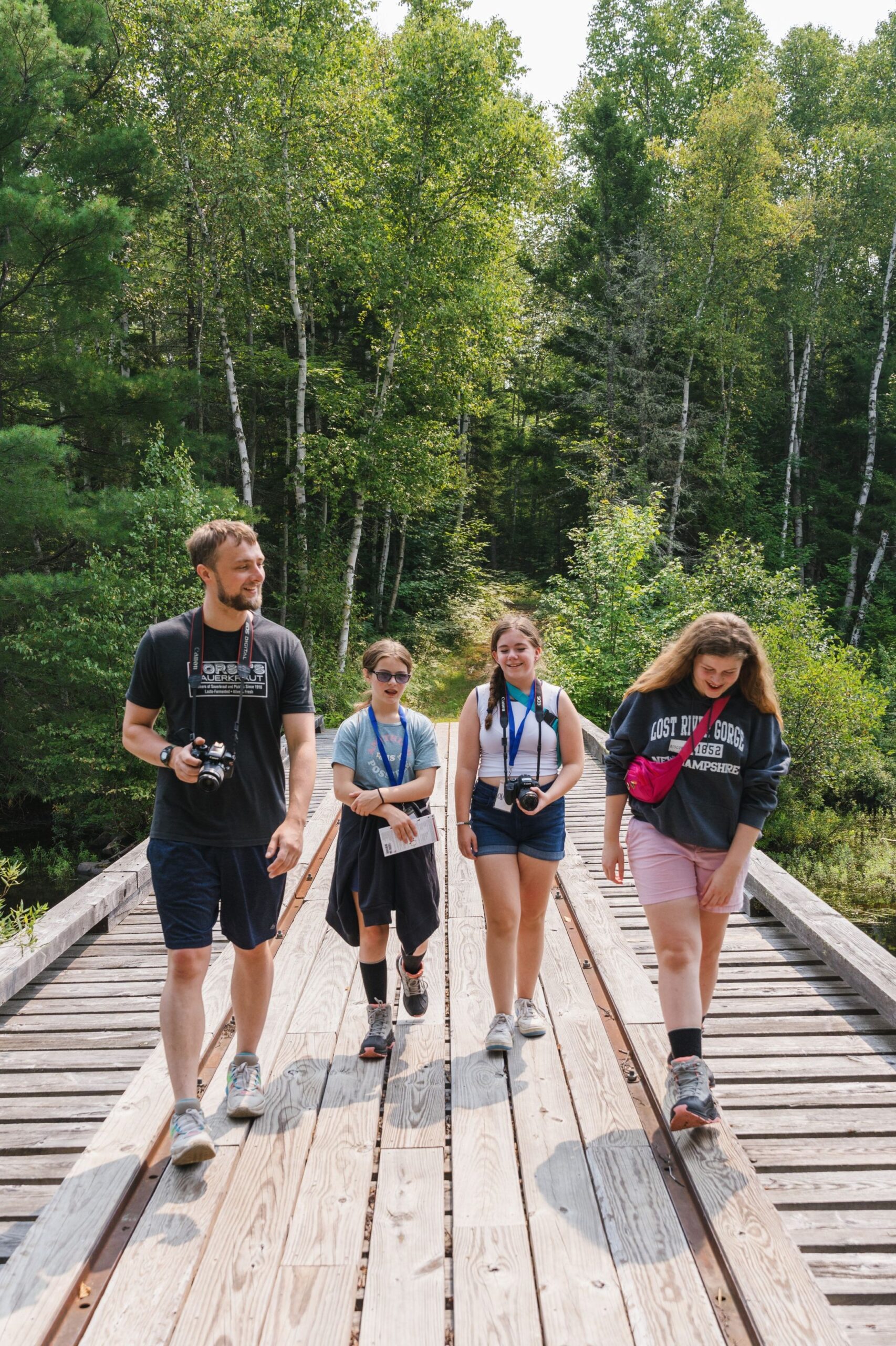Students with cameras walking on a bridge near Flagstaff Lake Hut in summer.